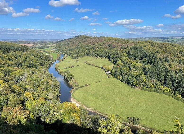 A river winding through a valley with green fields and dense forests. 5