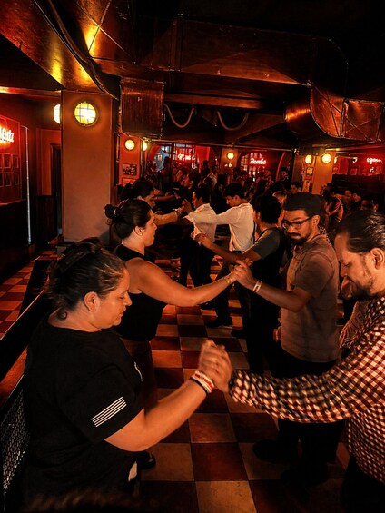 A crowded dance floor with people holding hands and dancing. 3