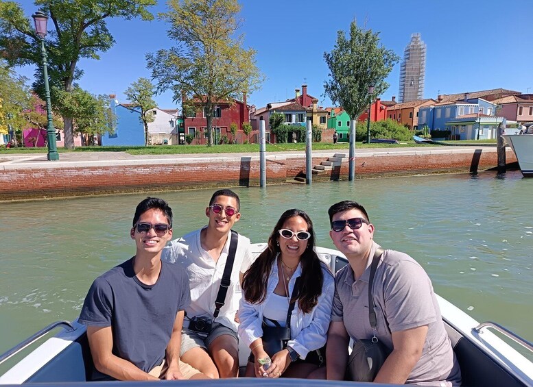A group of people on a boat in a canal with colorful buildings in the background. 1