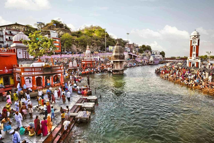 A crowded riverside with people, boats, and traditional architecture. 1
