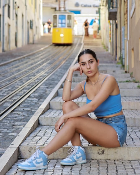 A person sitting on steps by train tracks with a tram in the background. 4
