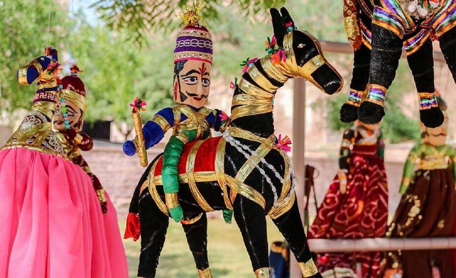 A person in a pink dress and another in a colorful costume riding a black and gold horse. 5