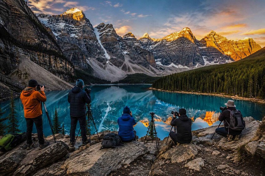 A group of photographers capturing a mountain lake with reflections at sunset. 3