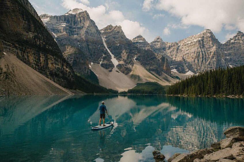 A person paddleboarding on a calm lake surrounded by mountains. 2