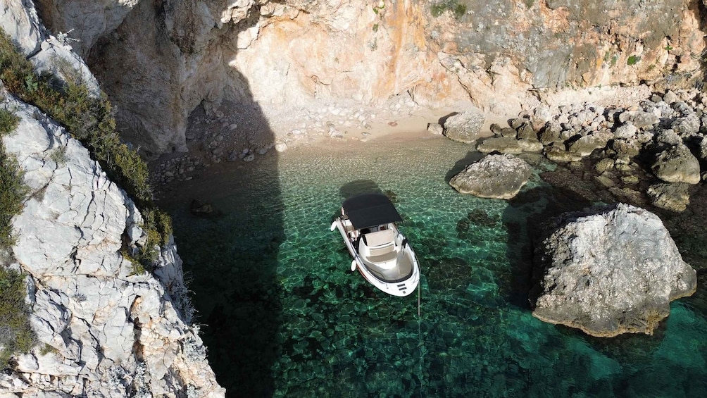 A boat in a clear, rocky cove surrounded by cliffs. 1