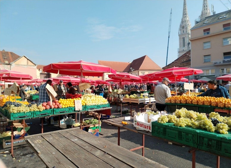 An outdoor market with vendors selling fruits under red umbrellas. 5