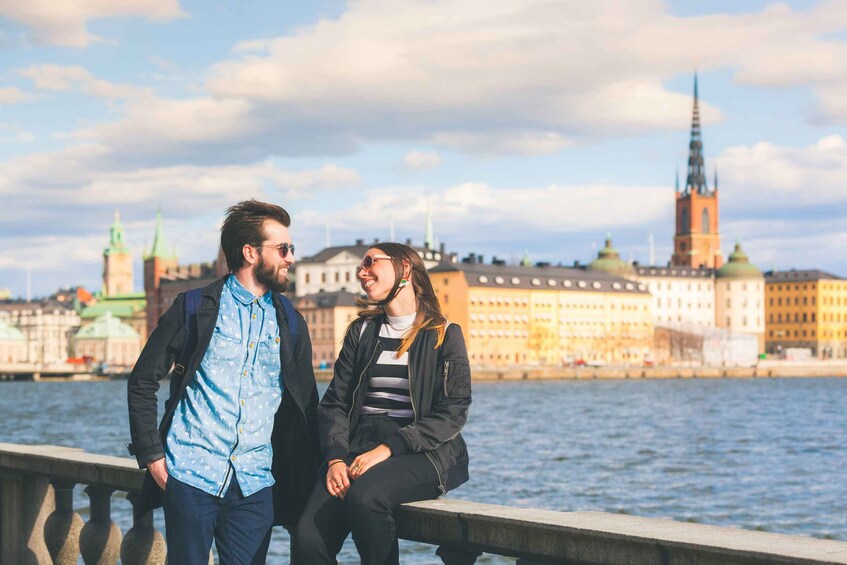 Pariskunta seisoo joen rannalla, ja taustalla näkyy kaupungin siluetti. 2