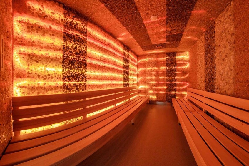 A sauna with benches and walls covered in heated stones. 2