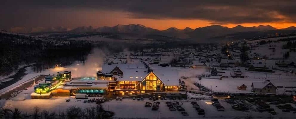 A snow-covered town with a prominent lodge and a mountain range in the background. 1