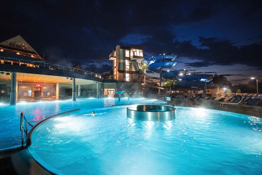 A swimming pool at night with a water slide and a building in the background. 5