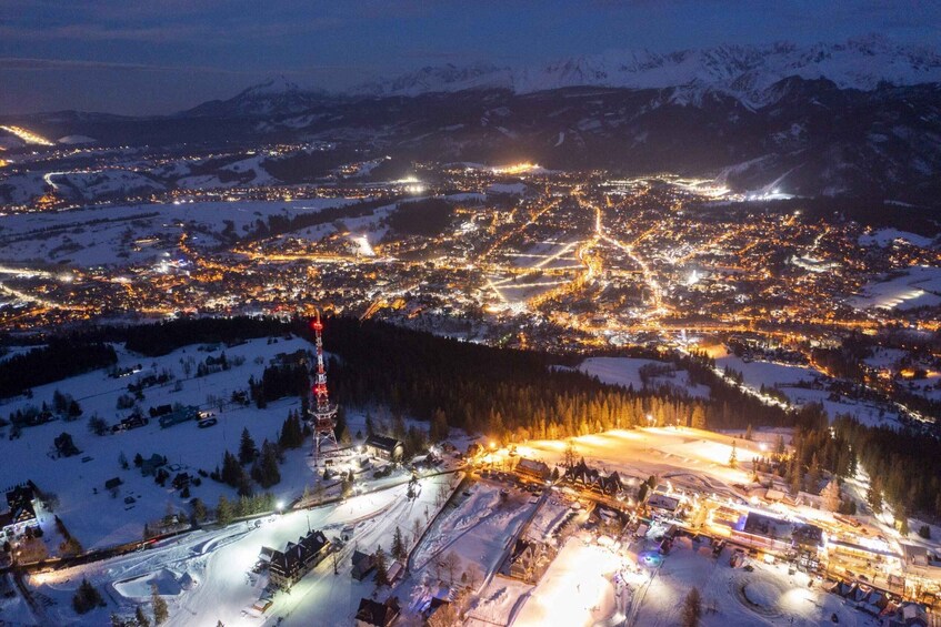 A snow-covered town at night with illuminated streets and buildings, surrounded by mountains. 3