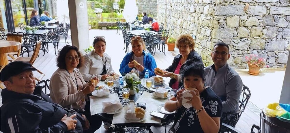A group of people dining at an outdoor restaurant with stone walls and metal chairs. 2