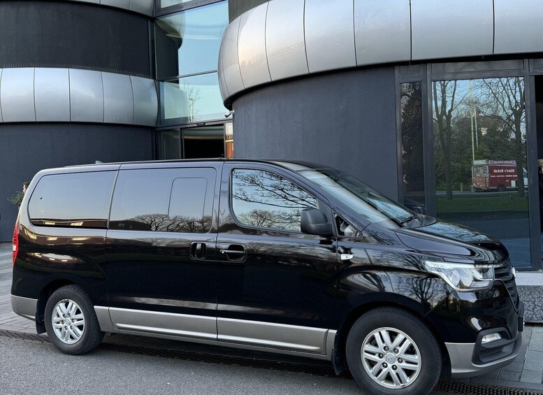 A black van parked in front of a modern building with curved glass windows. 3