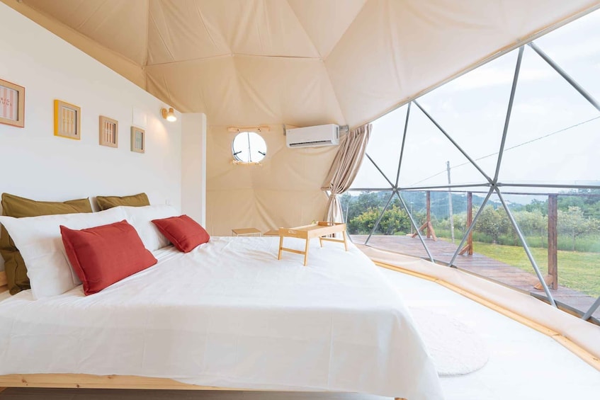 Une pièce spacieuse aménagée sous une tente, avec un grand lit, une petite table et une vue sur l’extérieur. 1