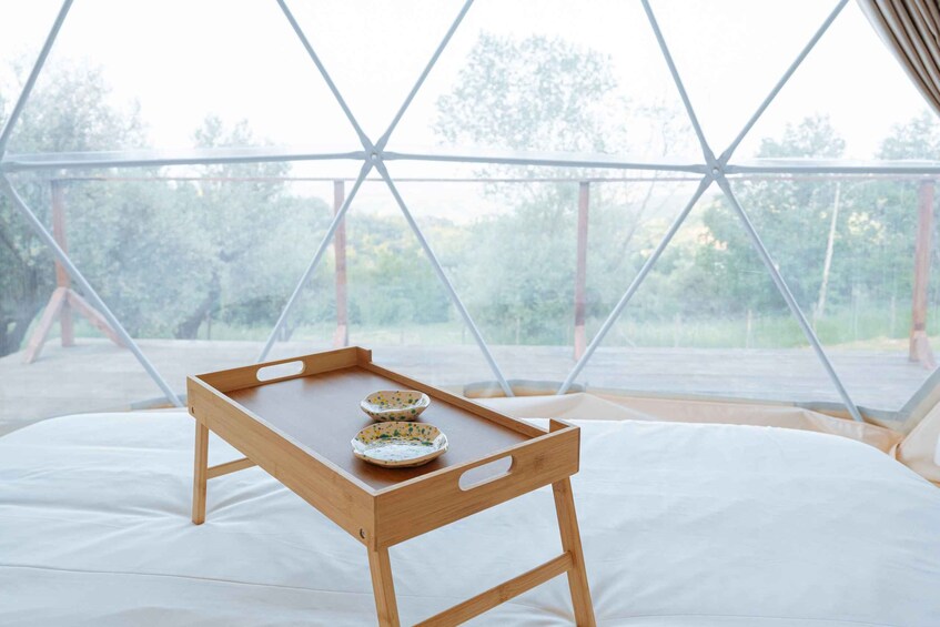 Un plateau en bois avec deux bols, posé sur un lit à l’intérieur d’une structure en forme de dôme géodésique. 2