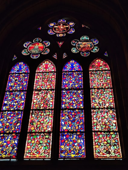A stained glass window with intricate floral patterns and a central emblem. 3