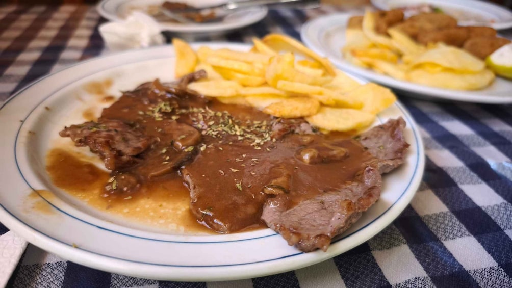 A plate of beef with gravy and fries. 3
