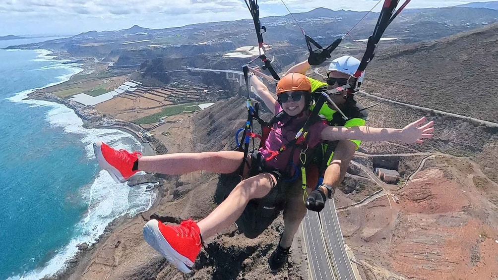 A person skydiving with a parachute over a coastal landscape. 1