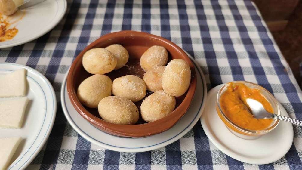 A bowl of round, golden-brown bread balls on a checkered tablecloth. 5