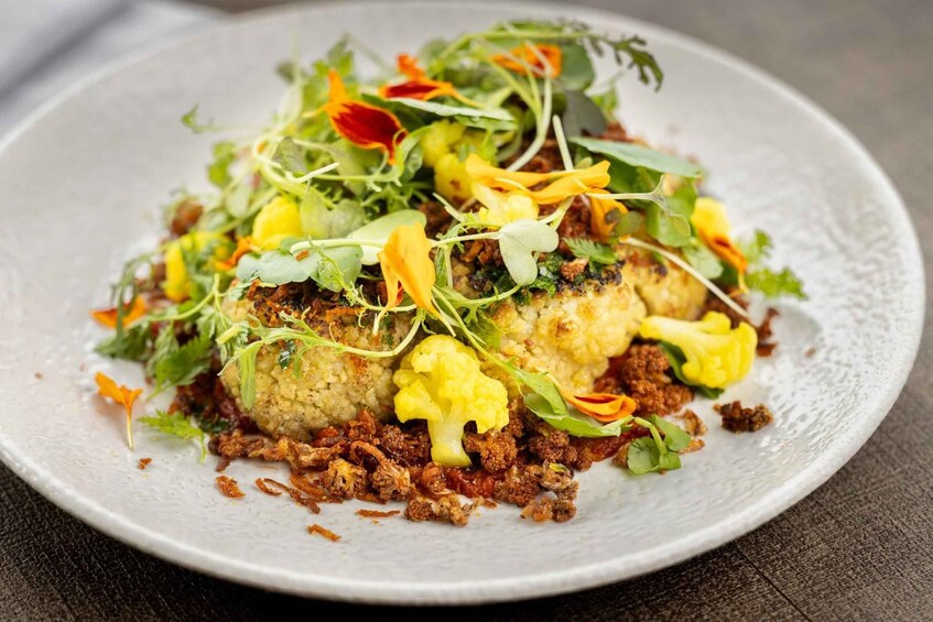 A dish with cauliflower, sprouts, and greens on a plate. 5