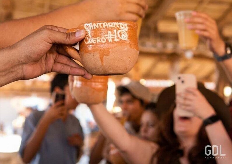 A person holding a ceramic cup with text on it, and another person holding a glass. 4
