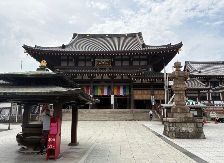 A traditional Japanese building with a tiled roof and a stone lantern in the foreground. 1