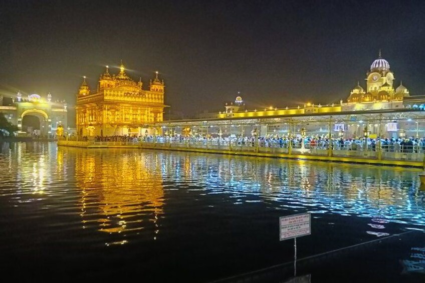 El Templo Dorado de noche con reflejos en el agua, un puente y una estructura en forma de cúpula. 3