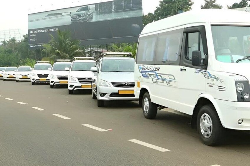 A line of white vans on a road with a billboard in the background. 4