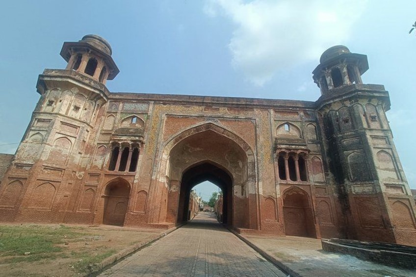 An arched gateway with intricate carvings, flanked by two towers, leading into a pathway. 3