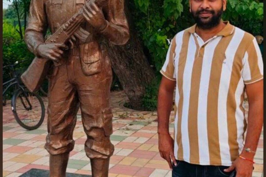 A person standing next to a bronze statue of a soldier holding a rifle. 2