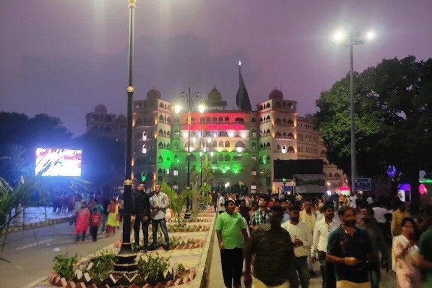 A large crowd gathered in front of a brightly lit building with multiple spires. 2