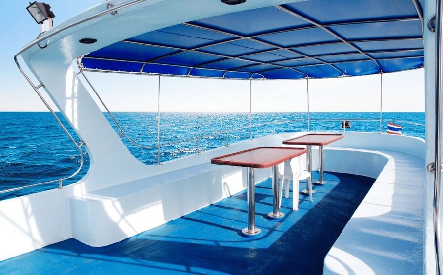 A boat deck with a blue canopy, two tables, and a flag. 3