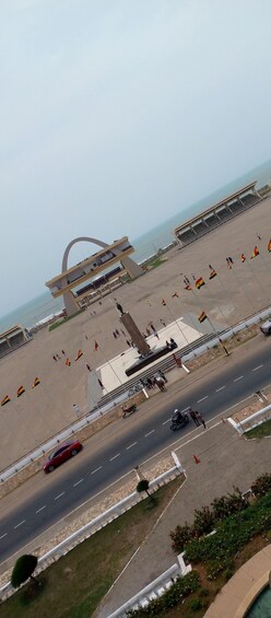 A coastal promenade with flags, a bridge, and a statue. 3