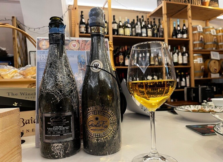 Two bottles of wine and a glass of wine on a table in a wine shop. 2