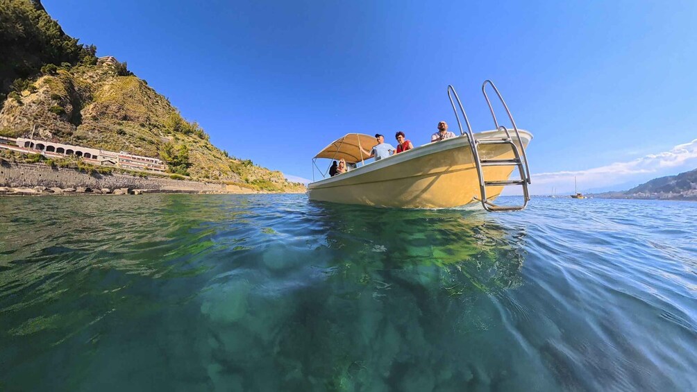 A boat on clear water with a mountainous coastline in the background. 5