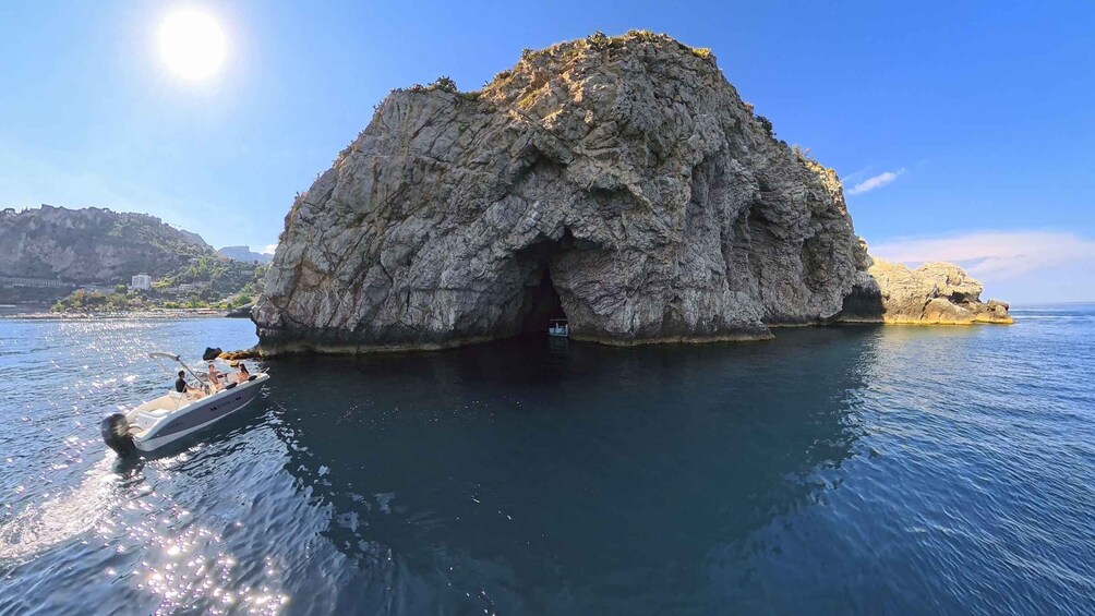 A rocky island with a cave entrance surrounded by calm water. 2