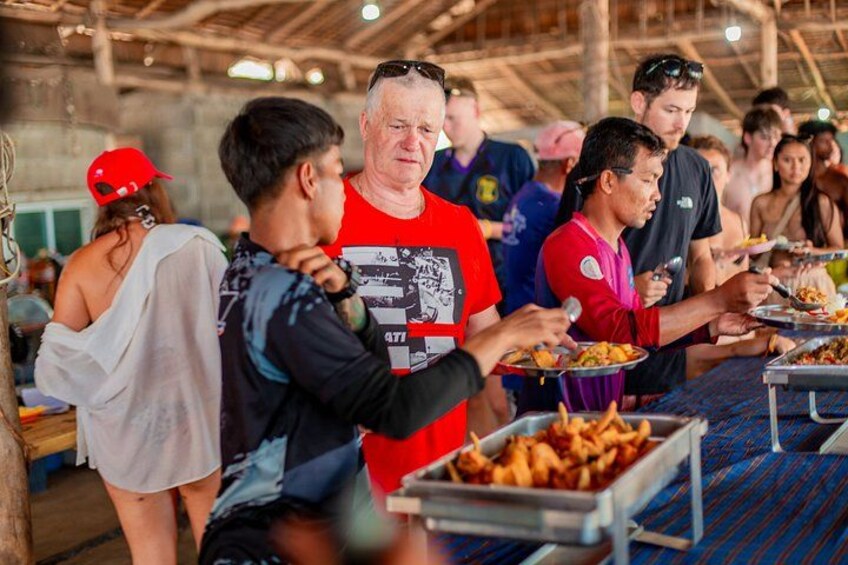 People serving themselves food at a buffet in a covered outdoor setting. 4