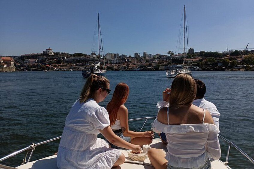 A group of people on a boat, a cityscape in the background, and a clear blue sky. 1