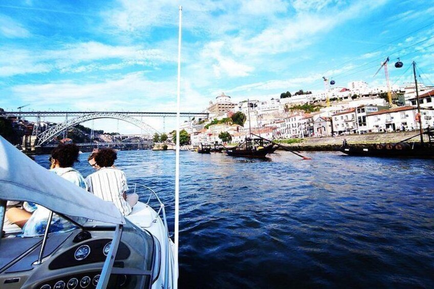 A boat on a river with a bridge in the background and buildings along the riverbank. 3