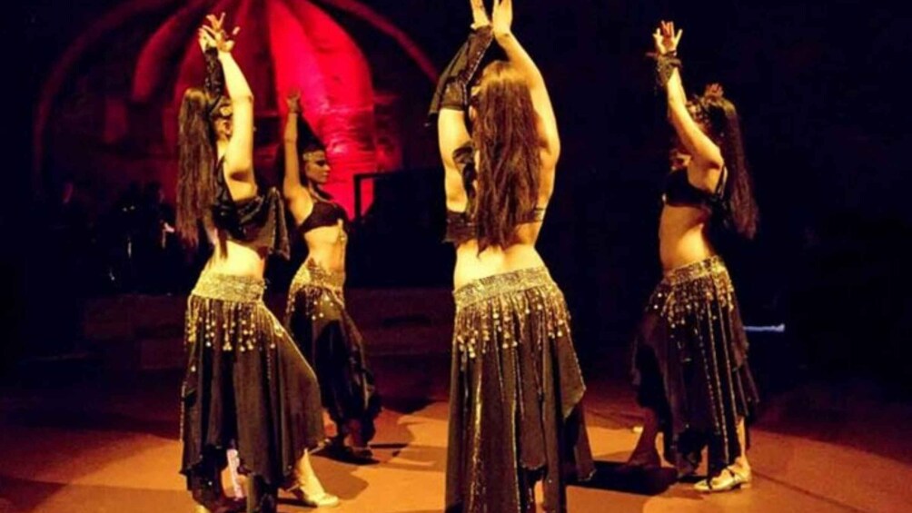 A group of belly dancers performing on stage. 1