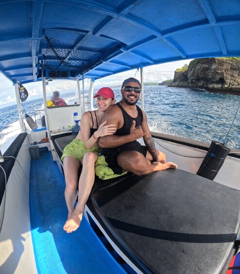 Two people on a boat with a rocky coastline in the background. 2