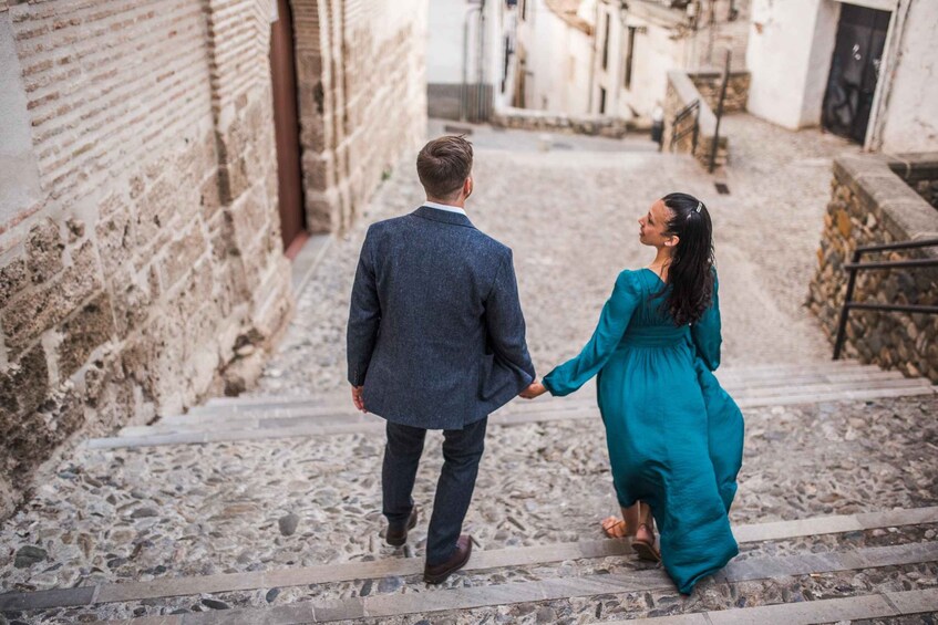 A couple walking down a cobblestone street in a historic town. 5