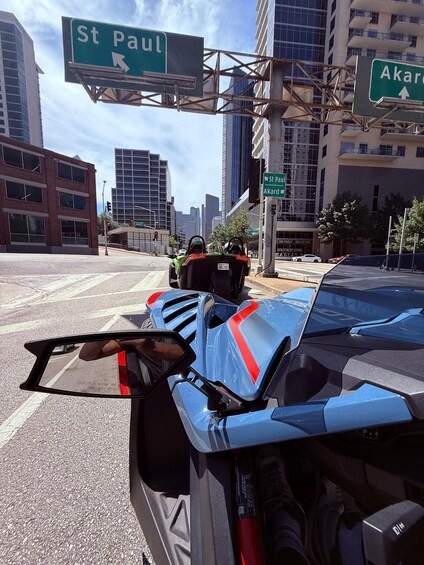A street view with a blue car, a motorcycle, and a street sign for St Paul and Akard. 4