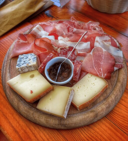 A charcuterie board with various cheeses, cured meats, and a dipping sauce. 2