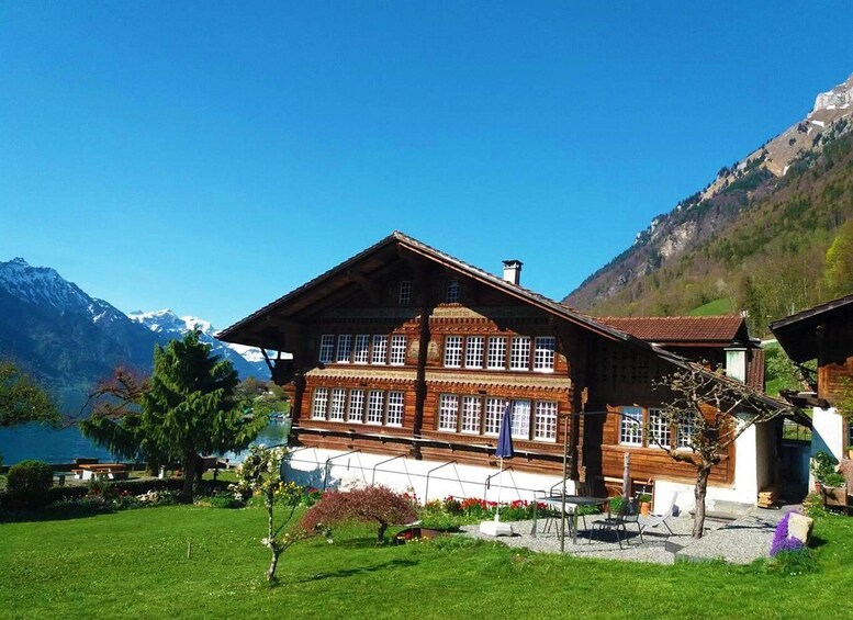 A wooden chalet with a balcony, surrounded by a well-maintained garden and a mountain backdrop. 3