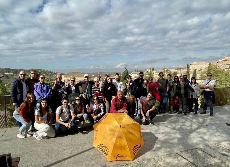 A group of people posing for a photo on a terrace with a yellow umbrella labeled 'VISITAS GUIADAS' in the foreground. 4