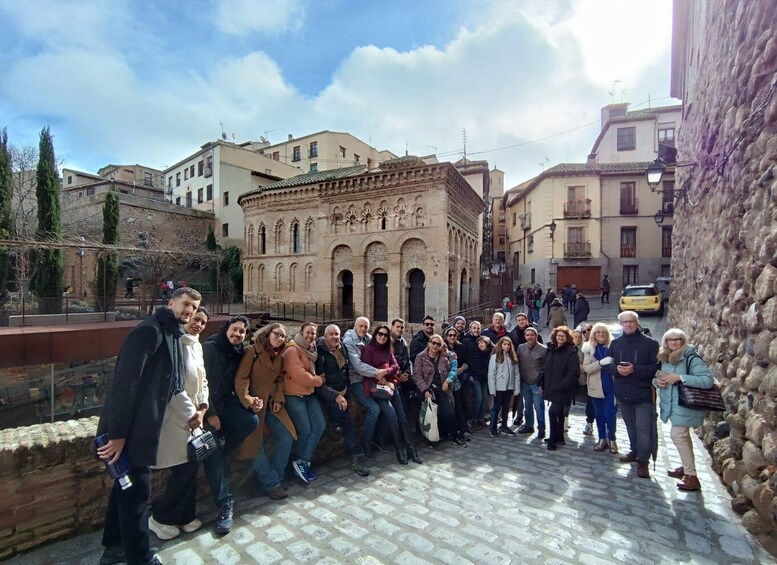 A group of people standing on a cobblestone street in front of a historic building with arches. 5