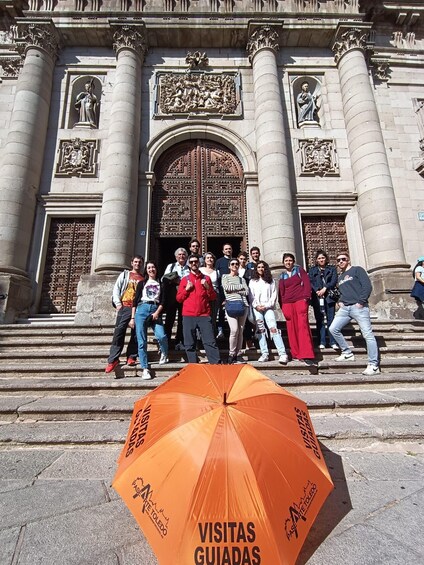A group of people standing in front of a historic building with ornate doors and columns. 3