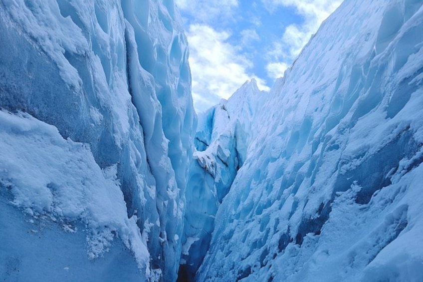 A deep glacial crevasse with steep, icy walls and a narrow passage. 2