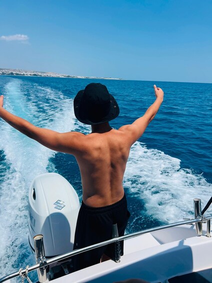 A person on a boat with arms outstretched, facing the sea. 3